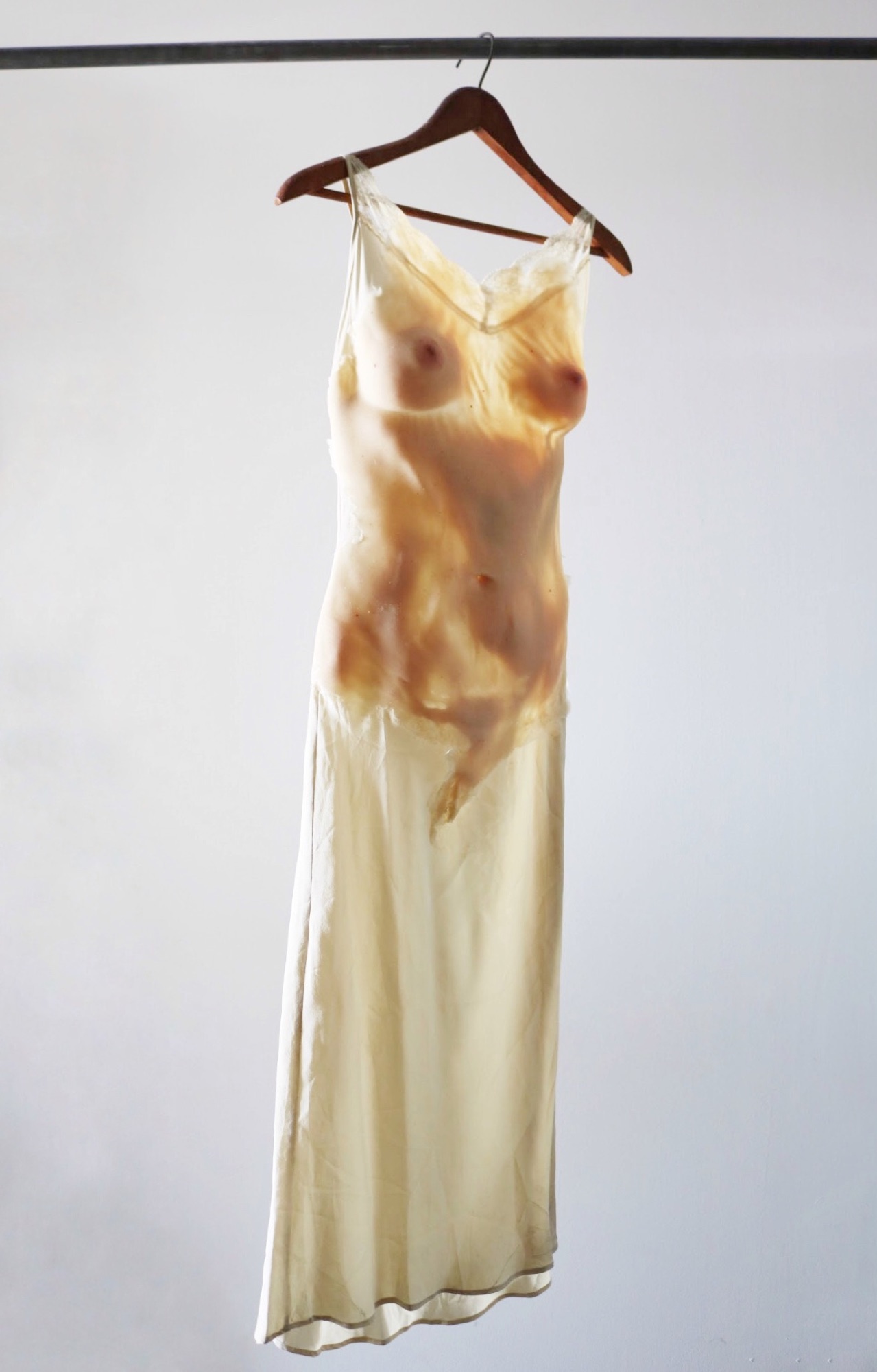 The silk nightgown on a hanger, stained with the silicone cast of a body