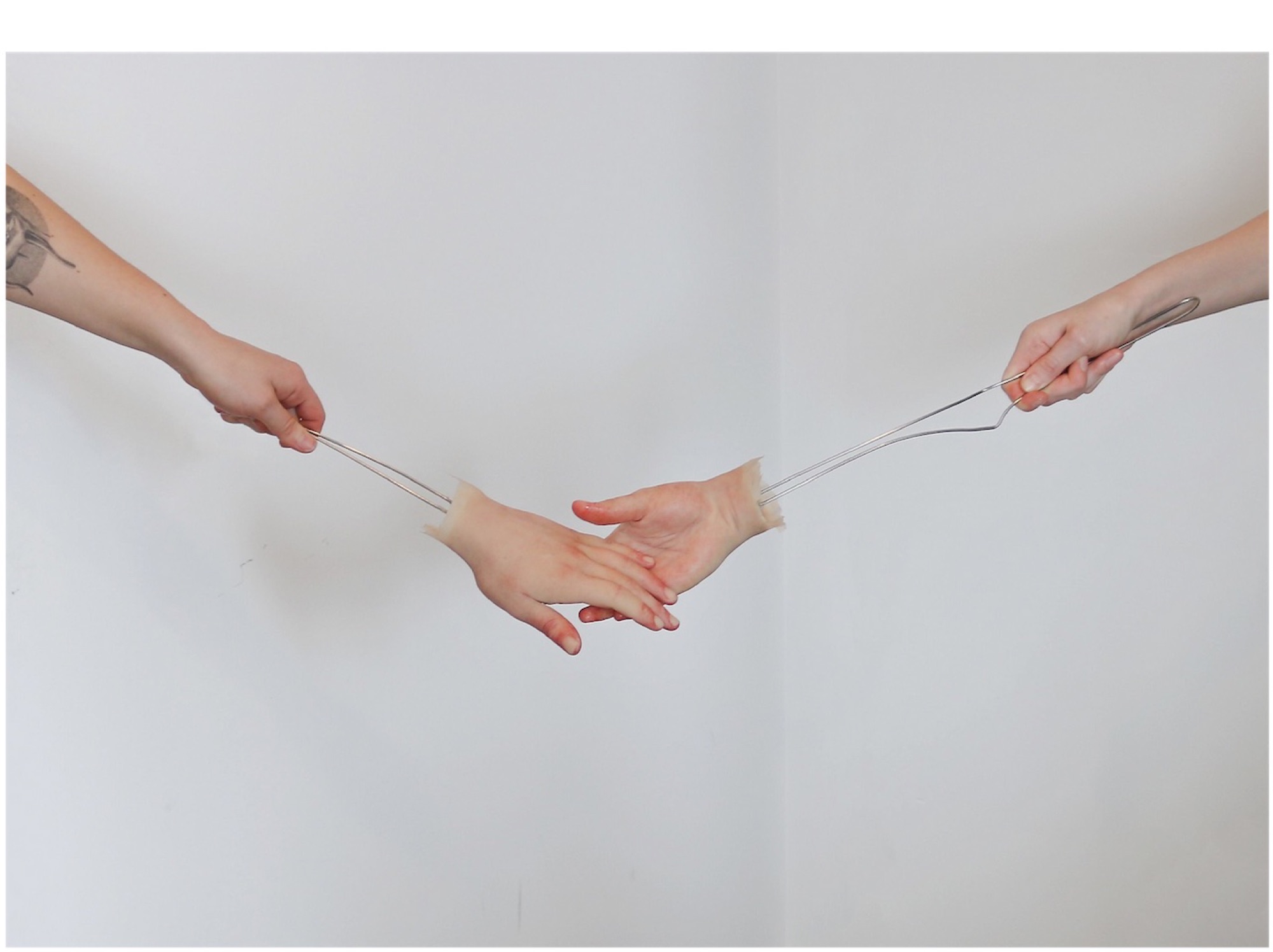 Two people hold aluminium rods joined by a pair of clasped silicone hands