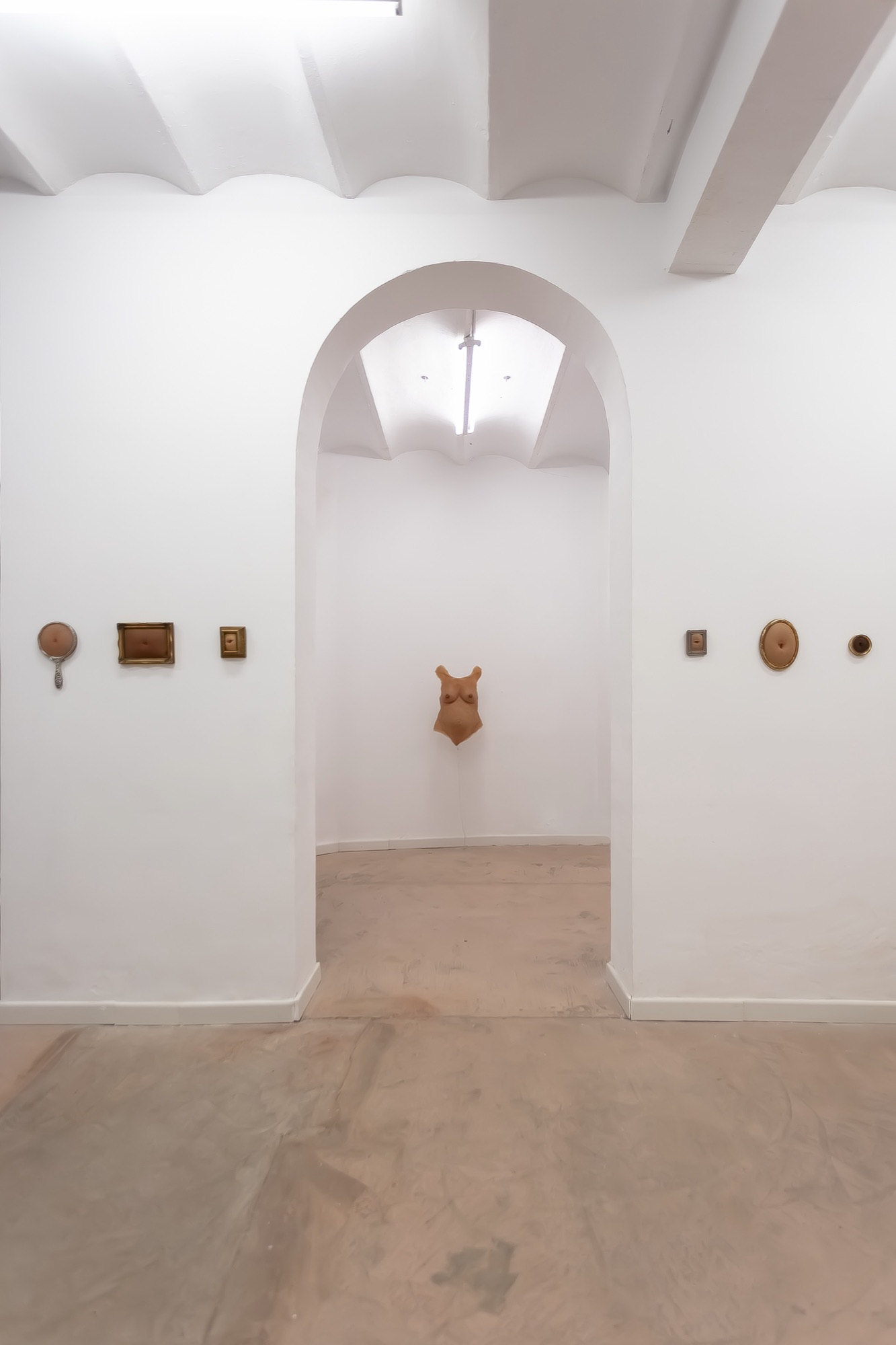 View through the gallery's arched doorway toward the torso on the far wall
