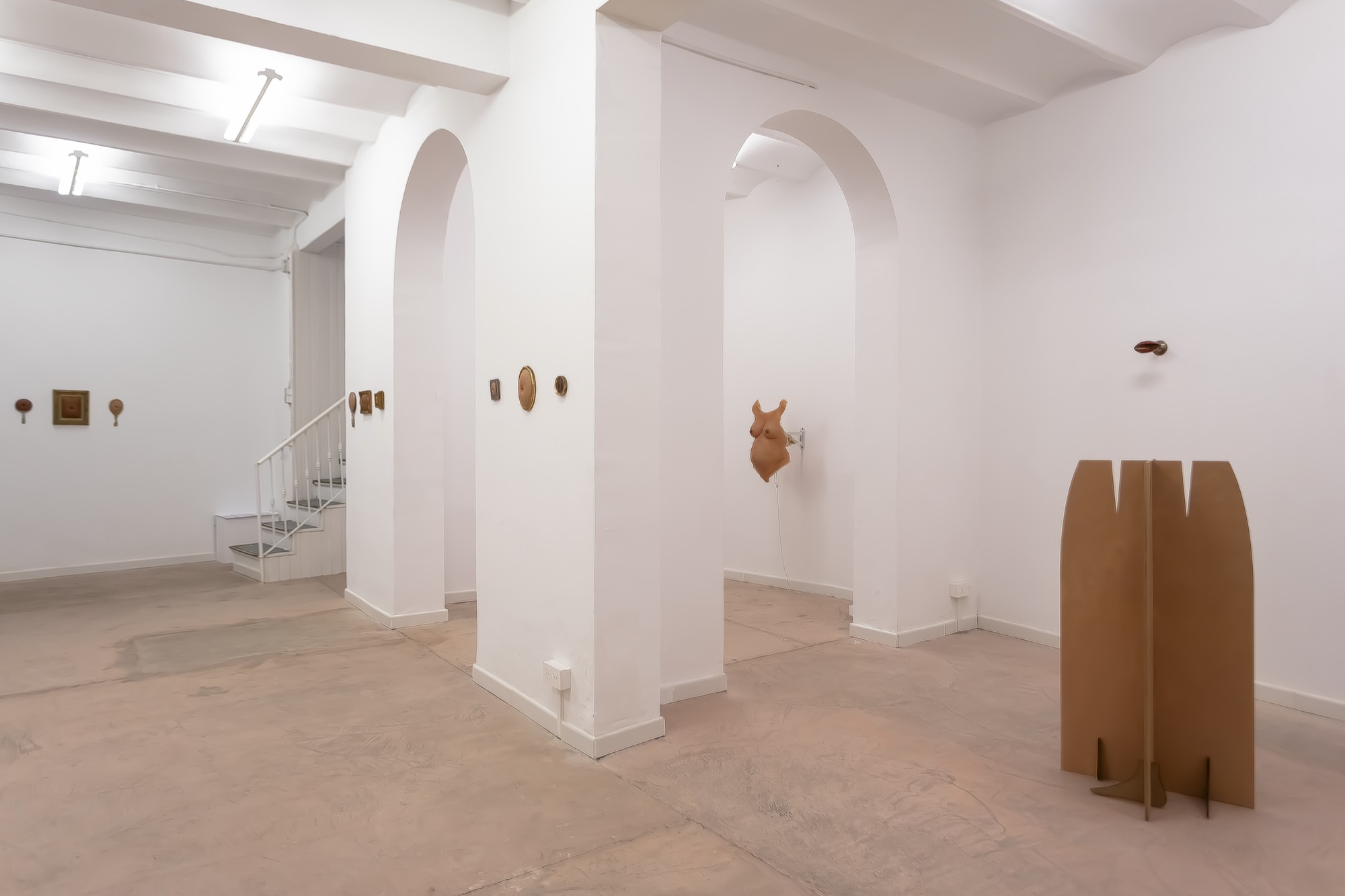 Installation view: small works on the walls, the torso at the back of the room and a sculpture on the floor